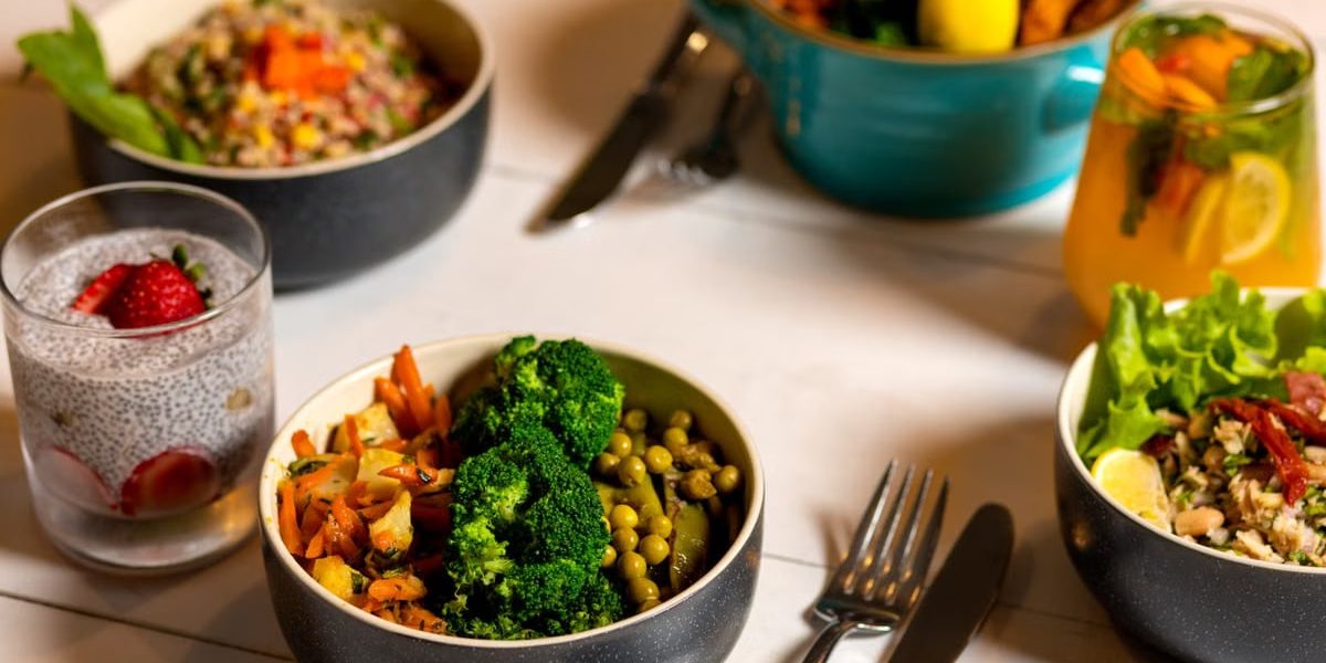Delicious colorful bowls of salad and fresh beverages on a white table, perfect for healthy dining.