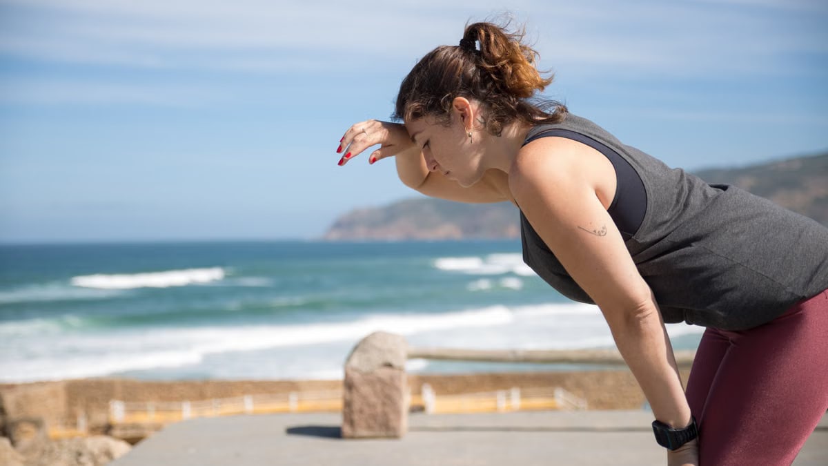 A woman rests after exercise, overlooking the ocean in Portugal's scenic seascape.